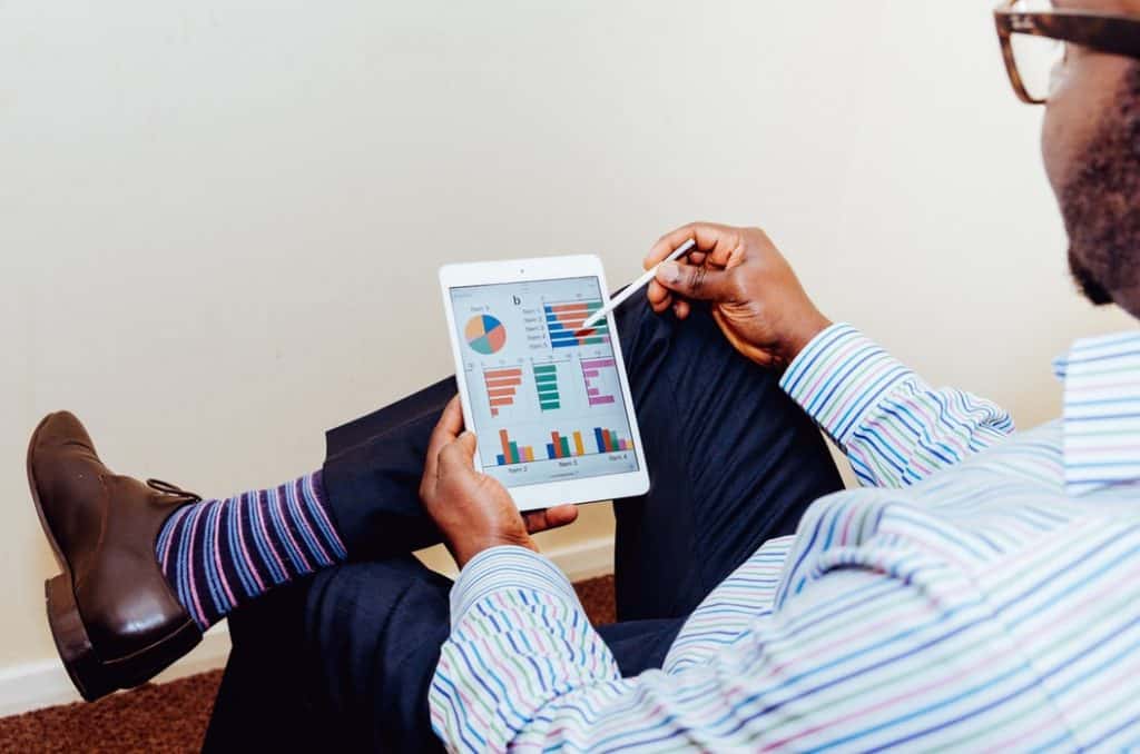 Man is shown wearing colorful socks and doing analytics on a tablet